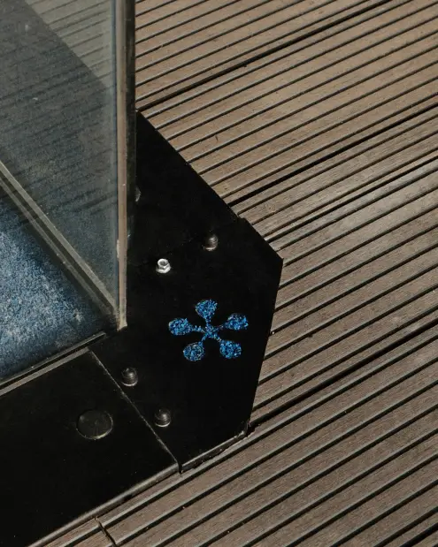 Glass panel corner with the Solace flower mark on the timber deck